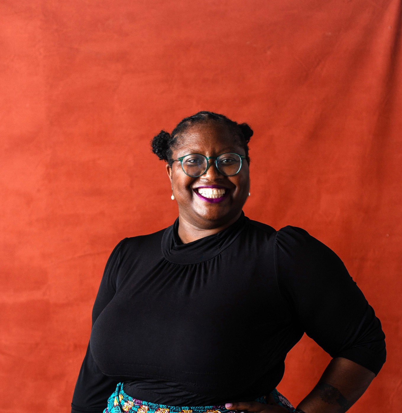 Alexis Appollonia Robinson, standing against a red backdrop