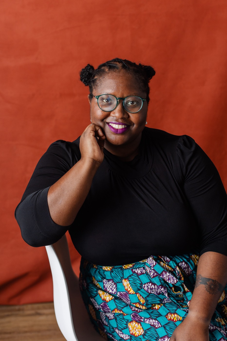 Alexis Appollonia Robinson seated against a red backdrop